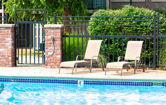 Two chairs are placed on the edge of a pool.