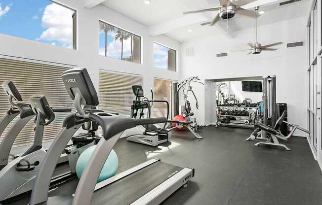 A modern gym with a treadmill, elliptical machines, and other exercise equipment.