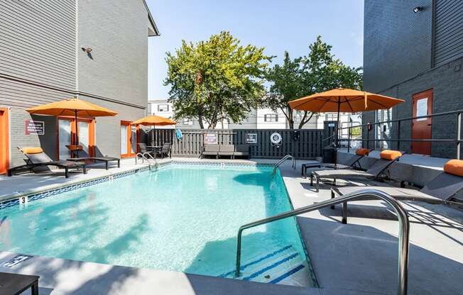 a pool with lounge chairs and umbrellas at the district flats apartments in lenexa