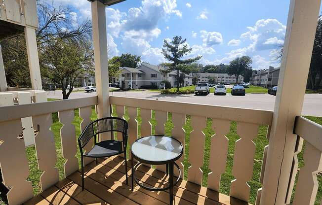 A balcony with a chair and table overlooking a street.