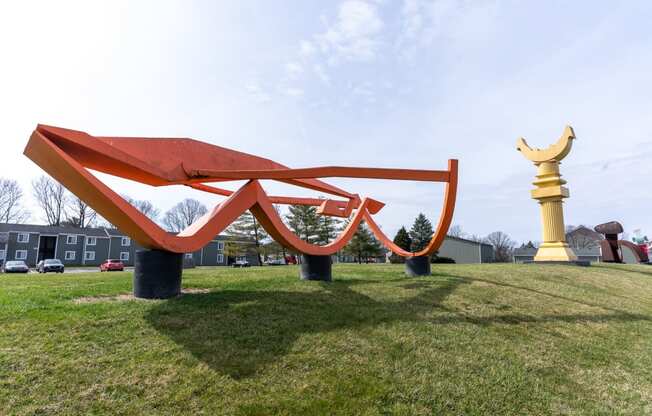 a large red sculpture in the middle of a field
