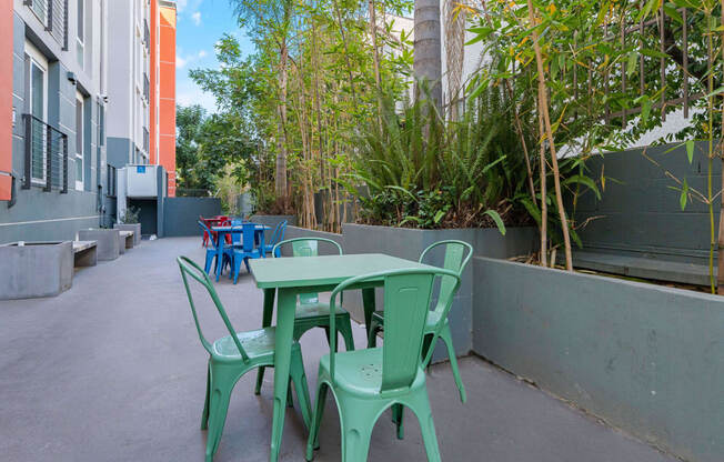 a patio with green tables and chairs and plants