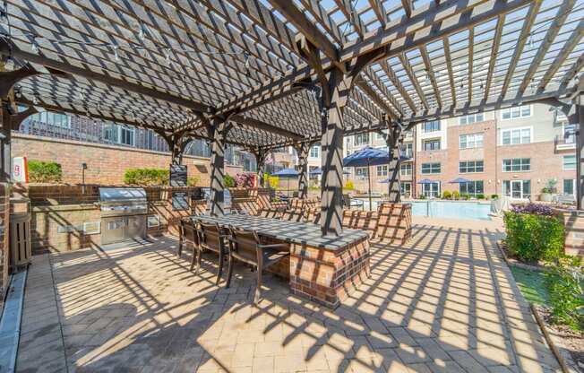 a pergola with a table and chairs on a brick patio