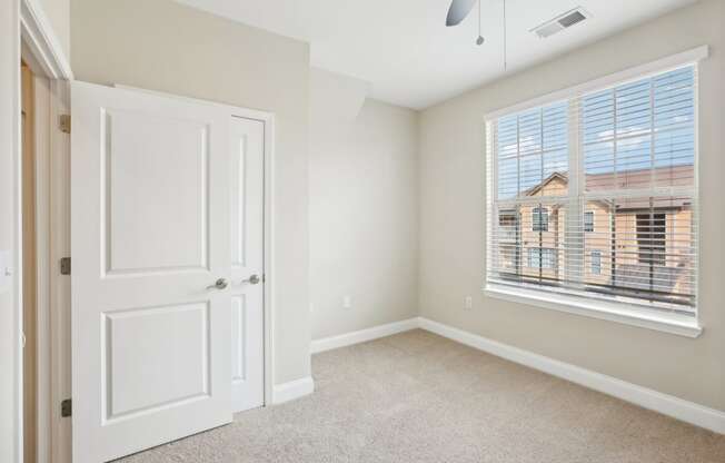 an empty bedroom with a large window and a white door