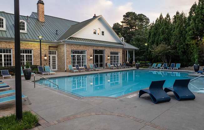 A pool area with a house and trees in the background.