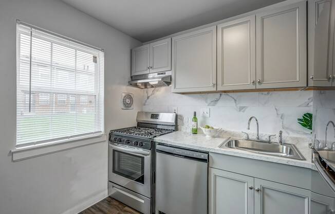 an all white kitchen with stainless steel appliances and a window