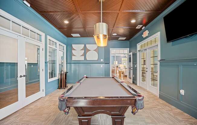 A pool table is in the middle of a room with a wooden ceiling.