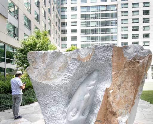 a sculpture of a hand on a rock in front of a building