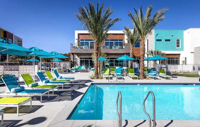 A pool area with sun loungers and palm trees.