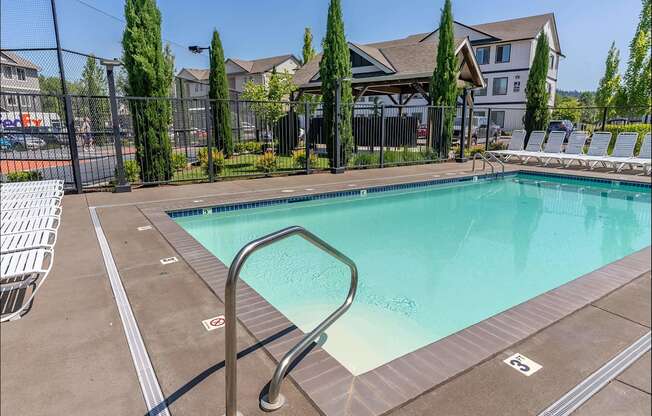 A pool surrounded by a fence and trees at Timberridge Place Apartment Homes, Albany, 97322