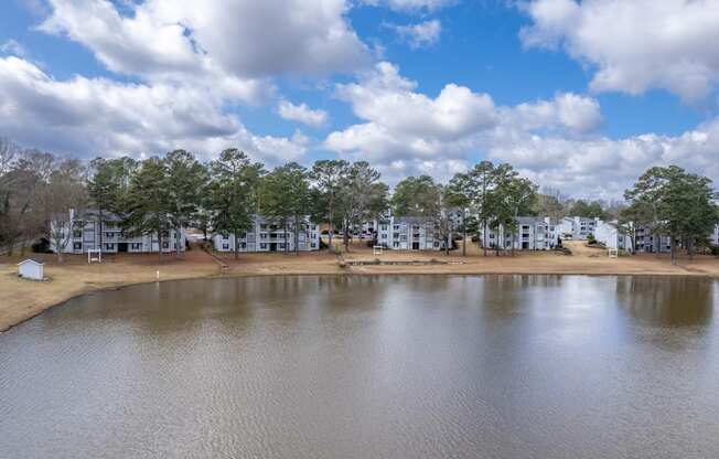 the view of a lake with apartments in the background and a cloudy sky