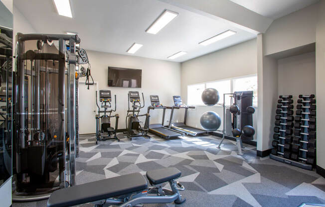 a large fitness room with cardio equipment and weights