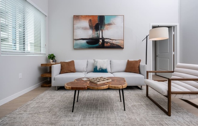 A living room with a white couch, a coffee table, and a painting on the wall.