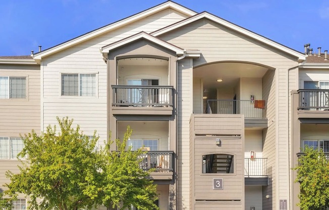 an apartment building with two balconies and a tree