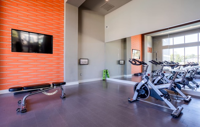 A gym with a brick wall and exercise bikes.