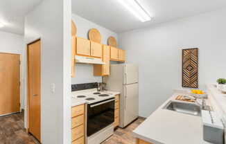 A kitchen with a white counter top and a white refrigerator.at Fifth Avenue Place Apartments, Oregon