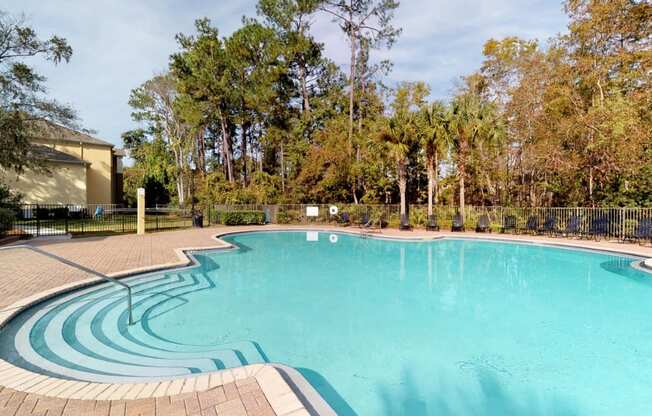 A large outdoor swimming pool surrounded by trees.