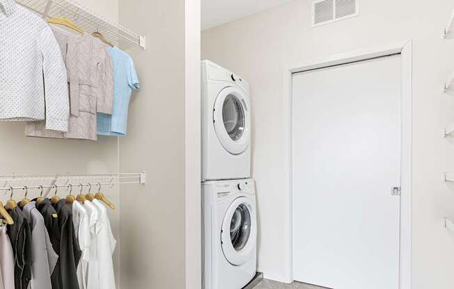 A laundry room with clothes hanging up and a washing machine.