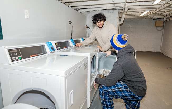 two people installing a washing machine in a laundromat