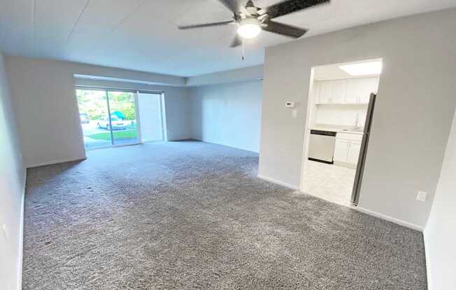 A spacious room with a ceiling fan and carpeted floor.