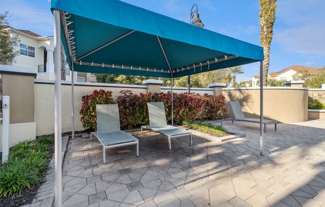 a patio with two lounge chairs under a canopy