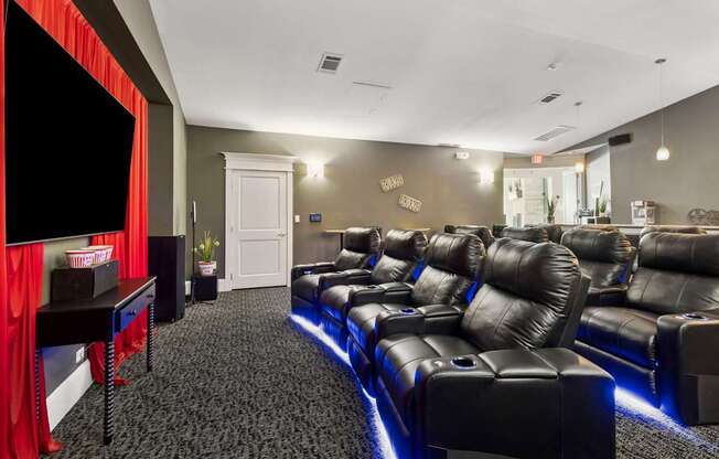 A home theater with black leather seats and a red curtain.