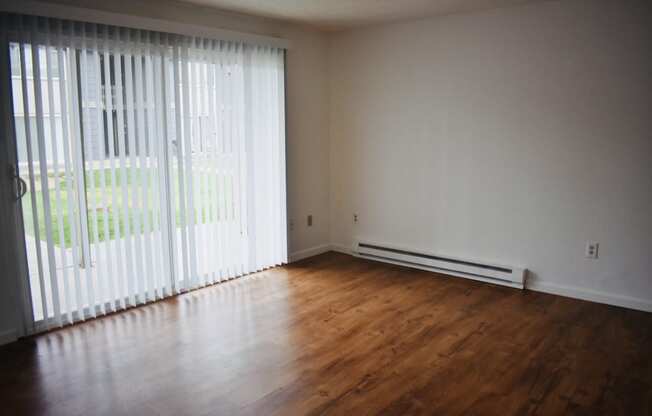 an empty living room with wood floors and white walls