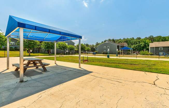 a picnic table sitting under a blue canopy in a park