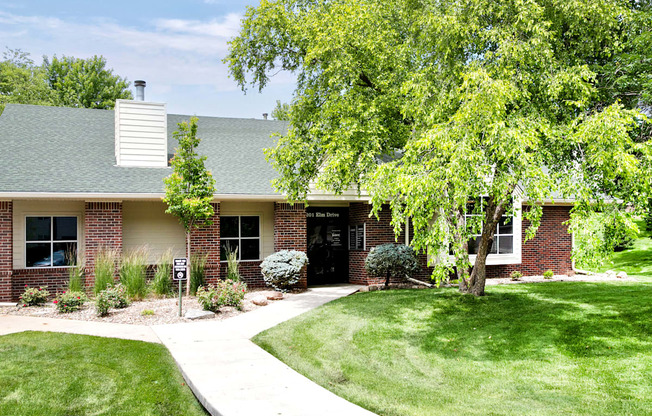 A house with a green lawn and a tree in front.