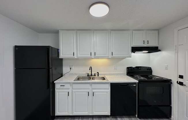 a kitchen with white cabinets and black appliances