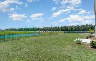 a large grassy area with a pond in the background