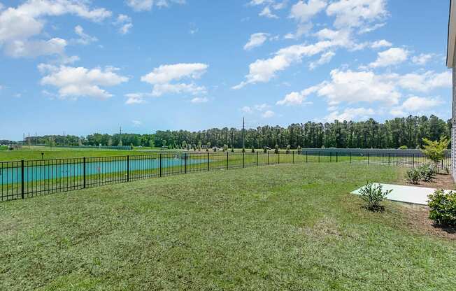 a large grassy area with a pond in the background