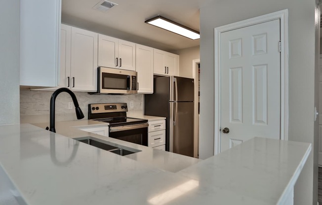 A kitchen with white cabinets and appliances.