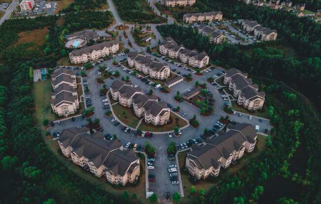 Aerial drone view of Riverstone Apartments with outdoor parking surrounded by lush green space