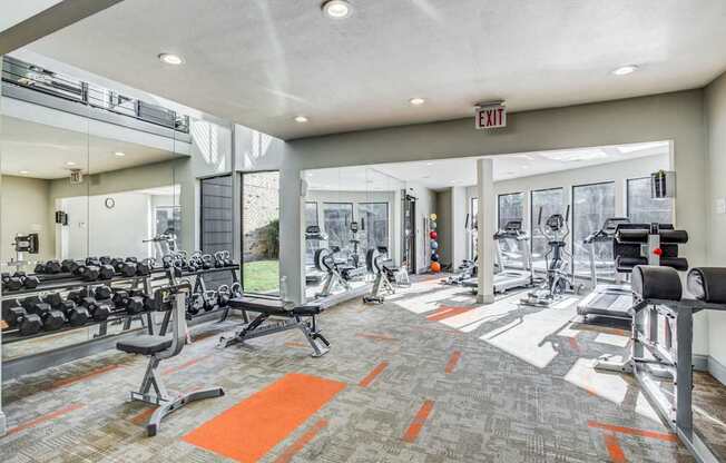 A gym with a variety of equipment including treadmills, weights, and exercise machines.