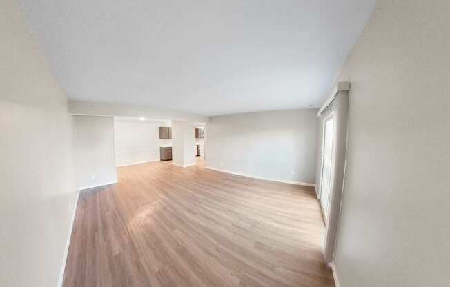 an empty living room with wood flooring and white walls