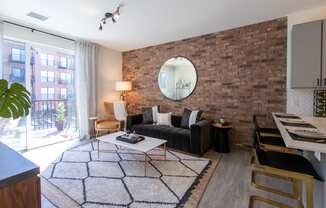 Maple Street Lofts - Spacious Living Room with Expansive Sliding Glass Door, Brick Accent Wall, and Furniture.