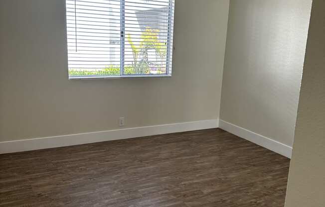 an empty room with wood floors and a window