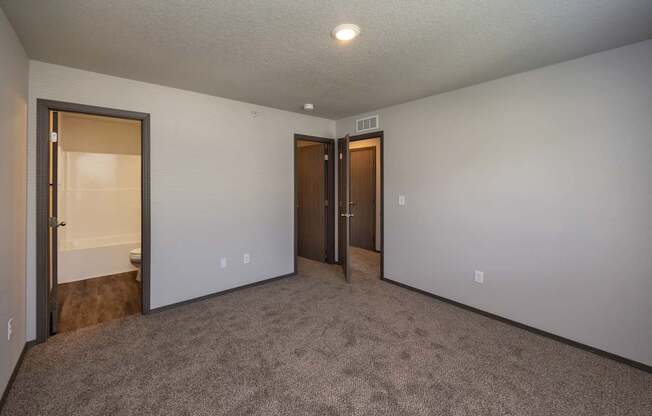 A room with carpeted floor and two doors.