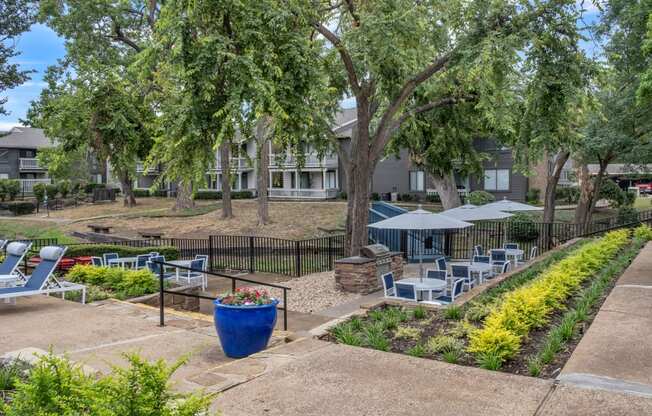 a courtyard with tables and chairs and trees in front of an apartment building