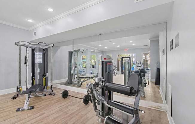 A gym with a mirror, weights, and exercise equipment.