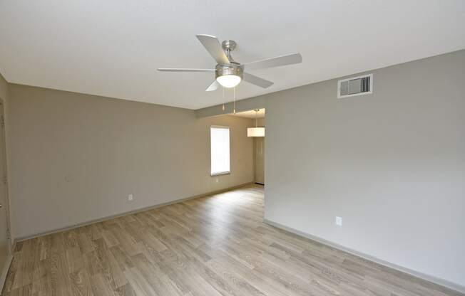 an empty living room with a ceiling fan