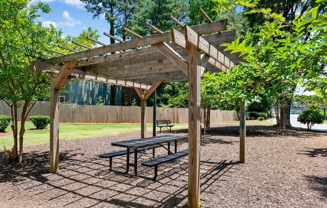 a picnic area with a bench and a pergola