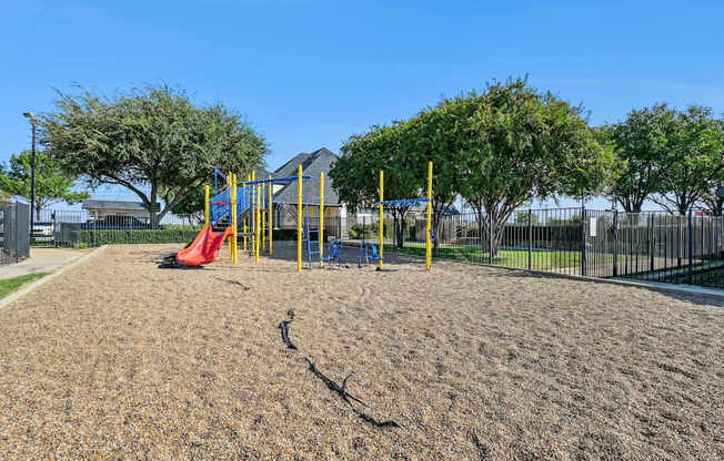 A playground with a yellow swing set and a red slide.