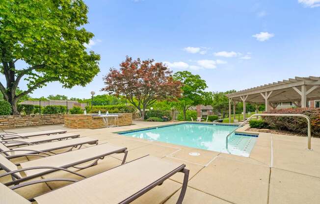 A pool surrounded by trees and chairs.