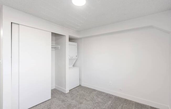 A white room with a carpeted floor and a doorway leading to another room.
