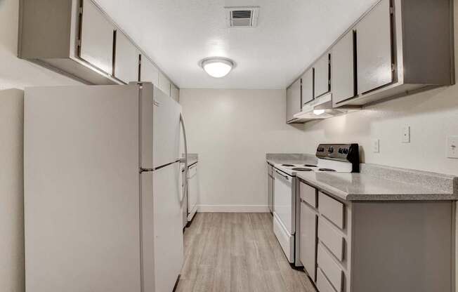 A kitchen with a white refrigerator and a white counter top.