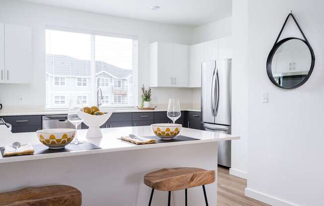 A modern kitchen with a white countertop and a large window.