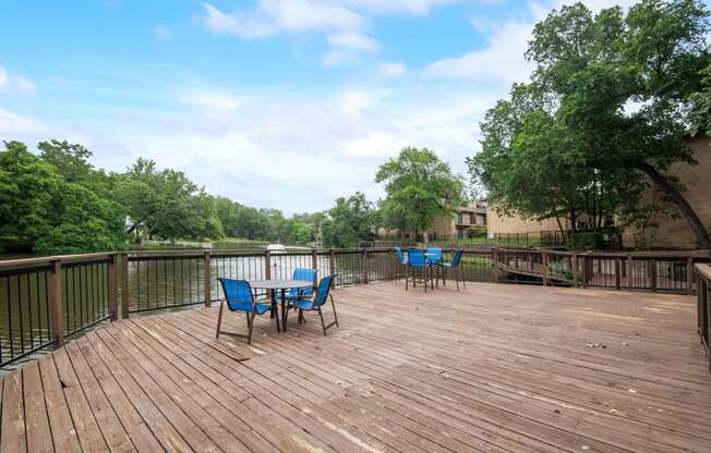 a deck with a table and chairs on it overlooking a body of water