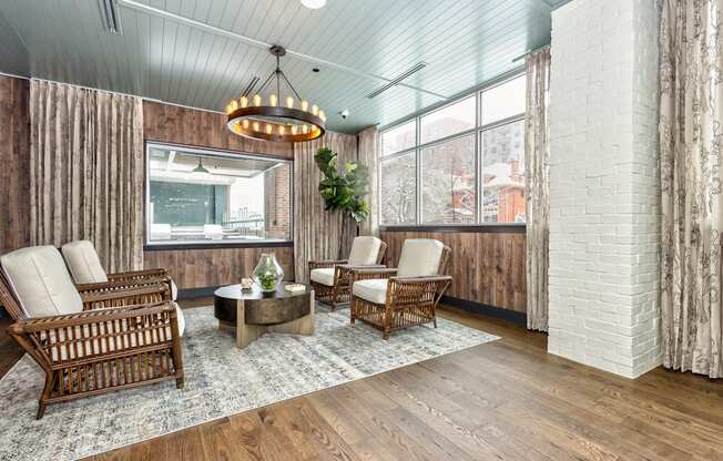 Resident common area with wooden furniture, modern style chandelier, and large windows at Sylvan Uptown, Colorado